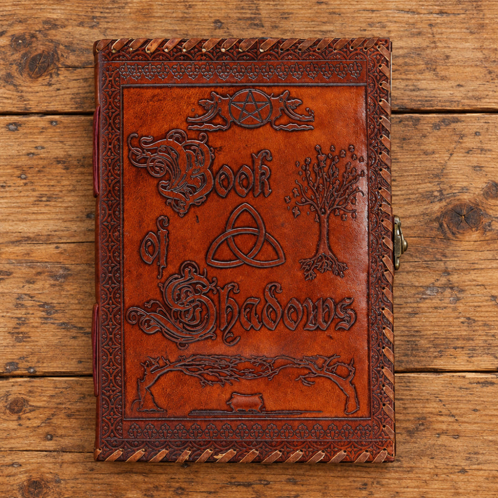 Brown leather book titled 'Book of Shadows' with embossed designs on a white background