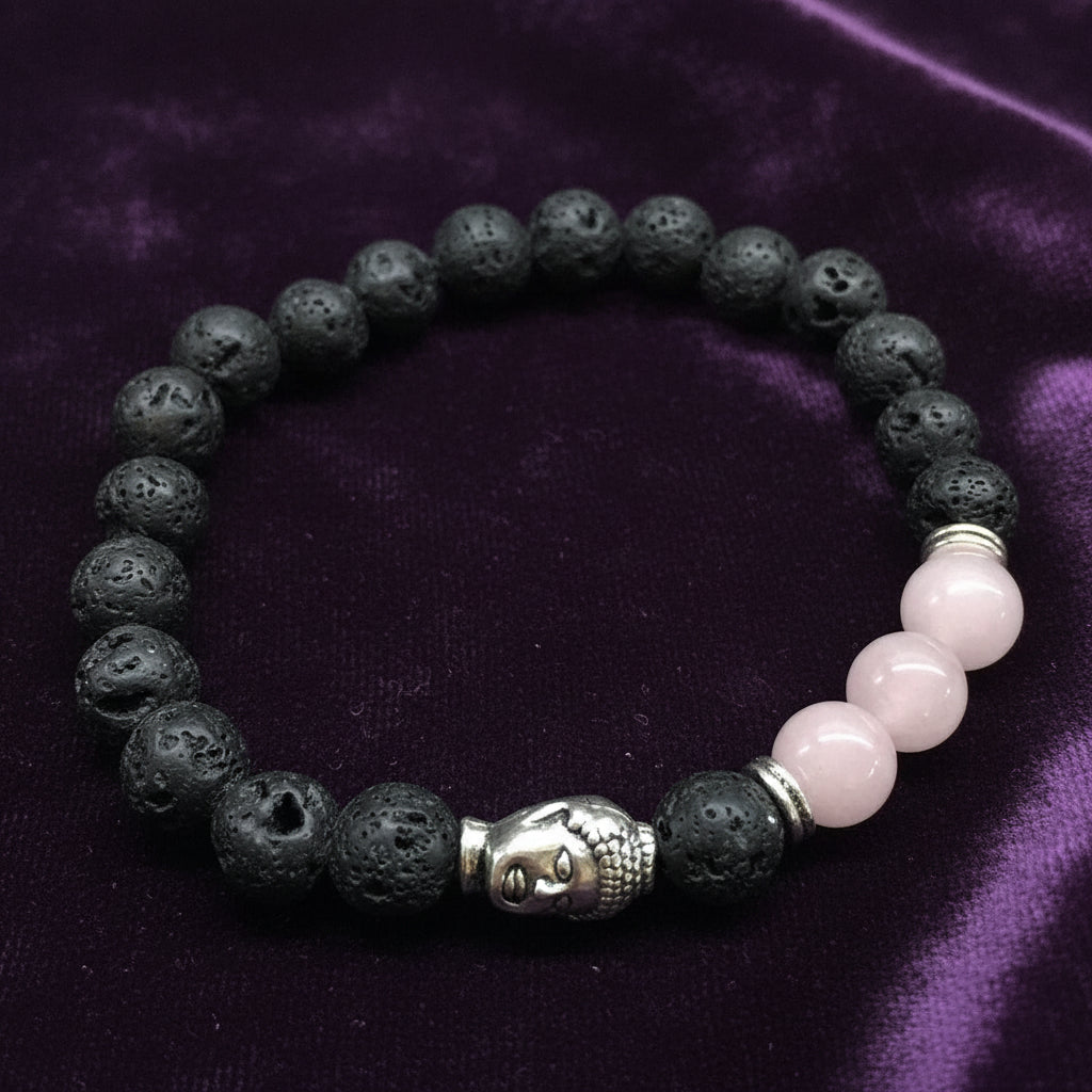 Bracelet with black lava beads, pink stones, and a silver Buddha head charm on a light gray background.