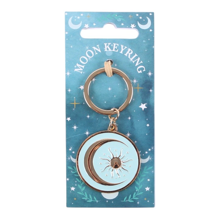 A moon keyring with a gold-tone metal key ring and a circular pendant featuring a crescent moon and sun design, attached to a blue printed backing card labeled 'MOON KEYRING'.