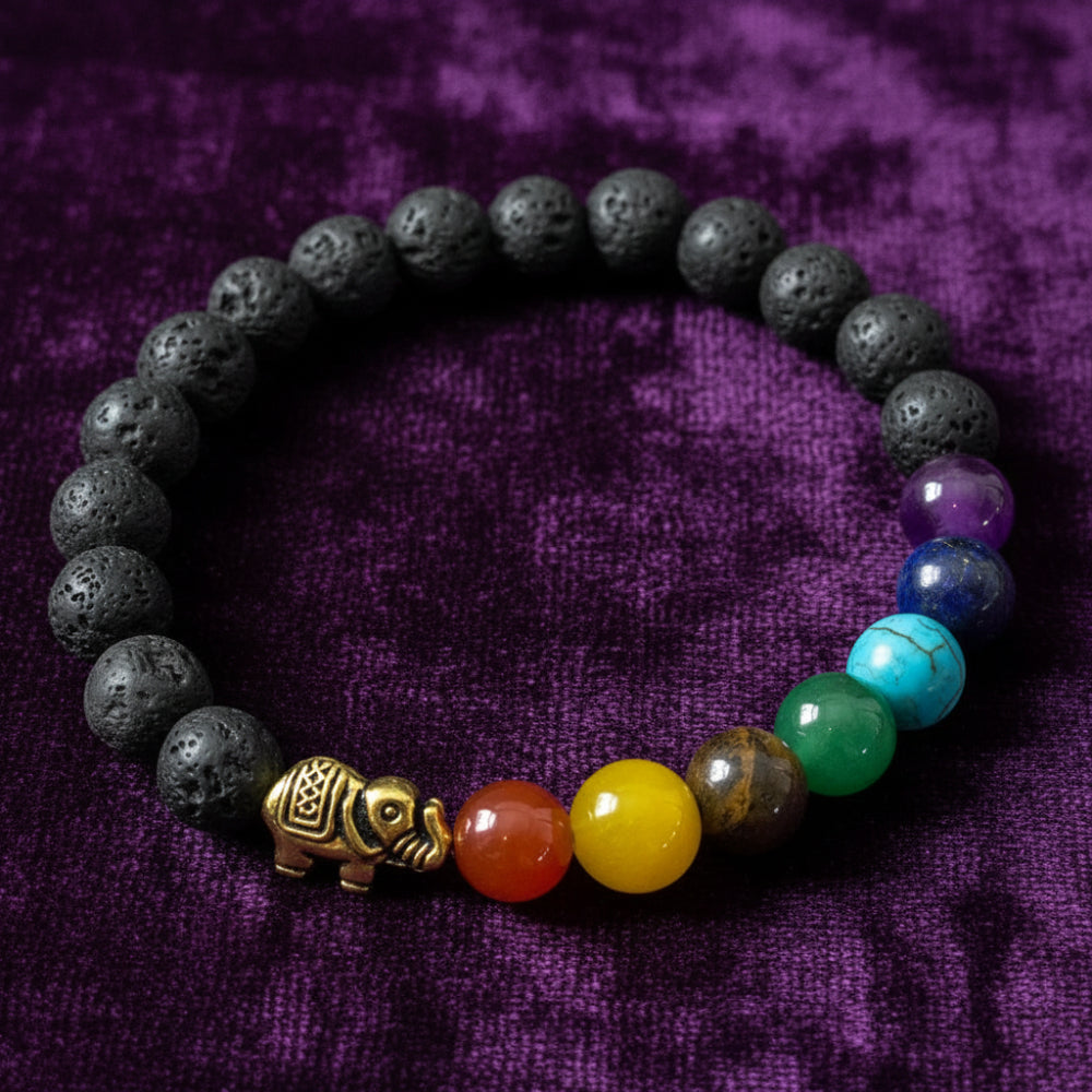 Multicolored beaded bracelet with a gold elephant charm on a gray surface