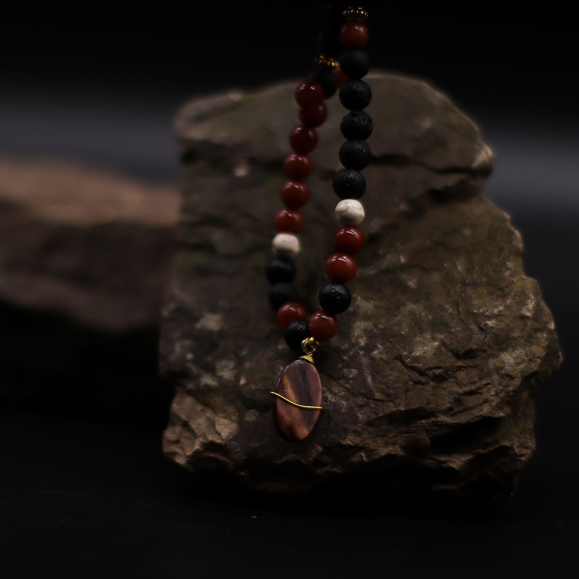 Beaded necklace with a pendant on a dark rock