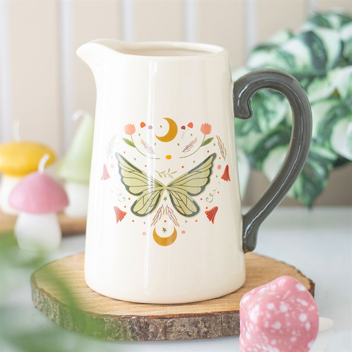 White ceramic pitcher with butterfly design on a wooden coaster