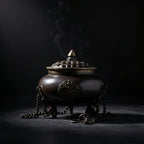 Bronze incense burner with smoke against a dark background at Eleanora Moon