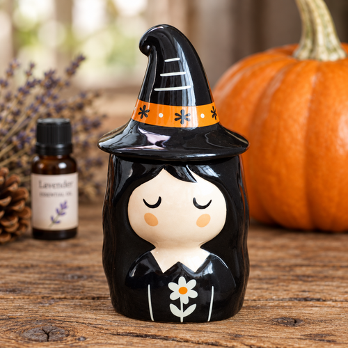 Decorative witch figurine with a pumpkin and bottle in the background