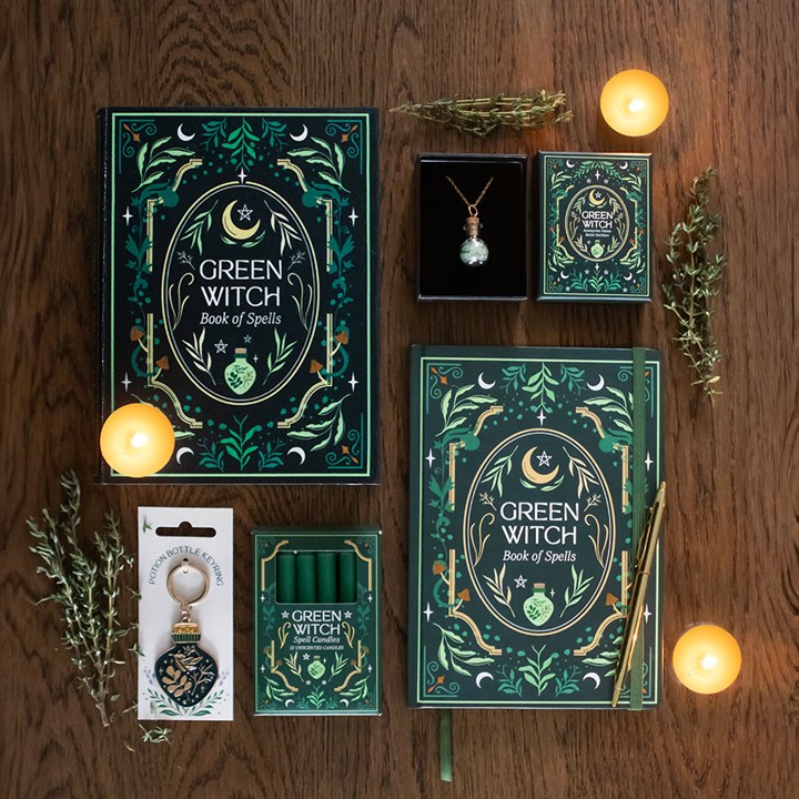 Collection of 'Green Witch' themed books, candles, and jewelry on a wooden surface.