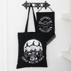 Black tote bag with witch-themed design and text, hanging on a wooden hook.