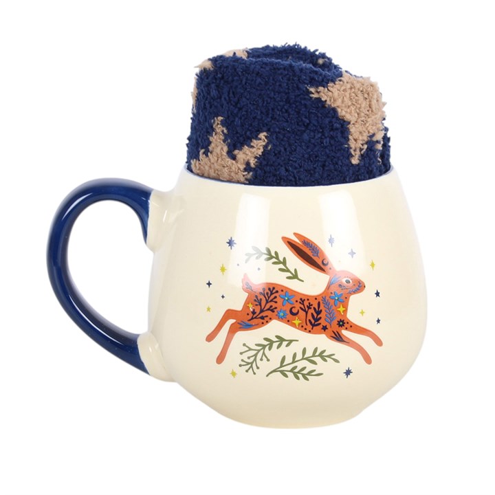 A cream-colored ceramic mug with a dark blue handle and interior, featuring a printed orange hare with blue and green details. A matching dark blue and beige textured fleece cup liner is propped up inside the mug against a plain white background.