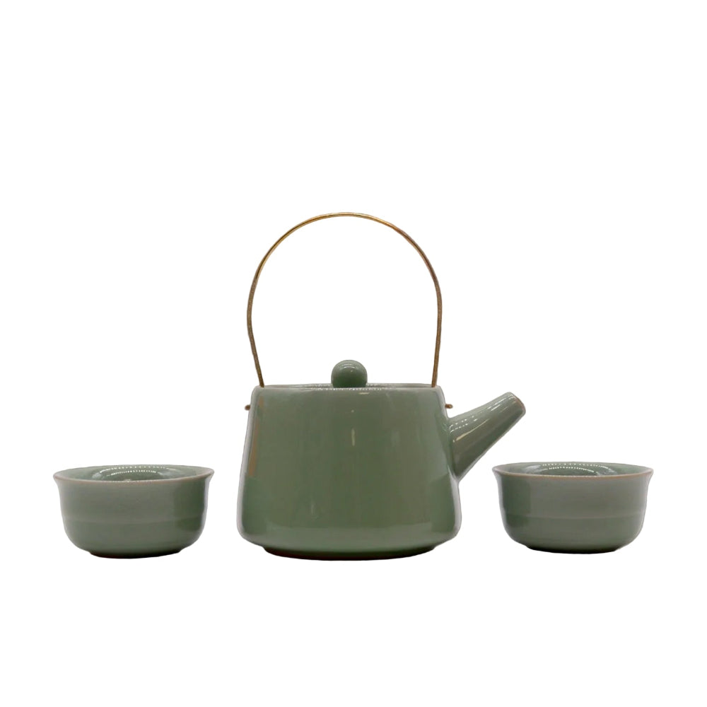 Green ceramic teapot with two matching cups on a reflective surface.