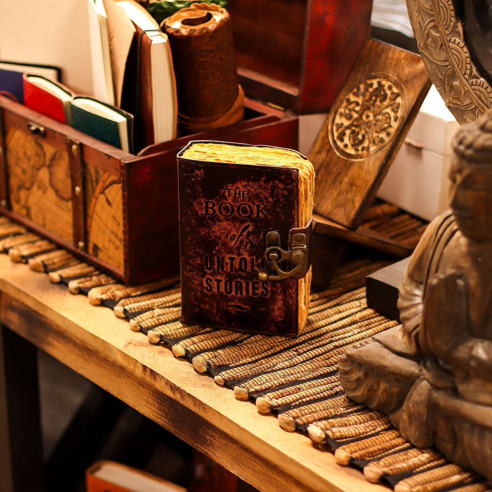 Decorative wooden book with intricate design on a shelf with books and a statue.