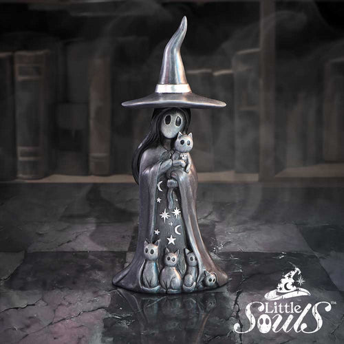 Metallic sculpture of a witch with a broomstick in a dark, gothic setting