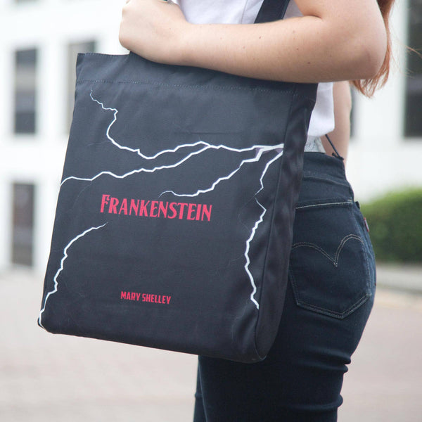 Person holding a tote bag with 'Frankenstein' and 'Mary Shelley' text.