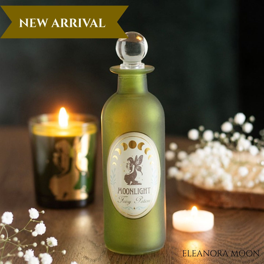 An olive green frosted glass apothecary-style bottle with a clear round stopper, labeled 'MOONLIGHT Sleep Powder,' displayed on a wooden surface with lit candles and white flowers in the background. A banner at the top reads 'NEW ARRIVAL' and 'ELEANORA MOON' appears at the bottom right.