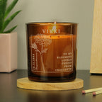 Personalized candle with engraved text and design on a wooden coaster.