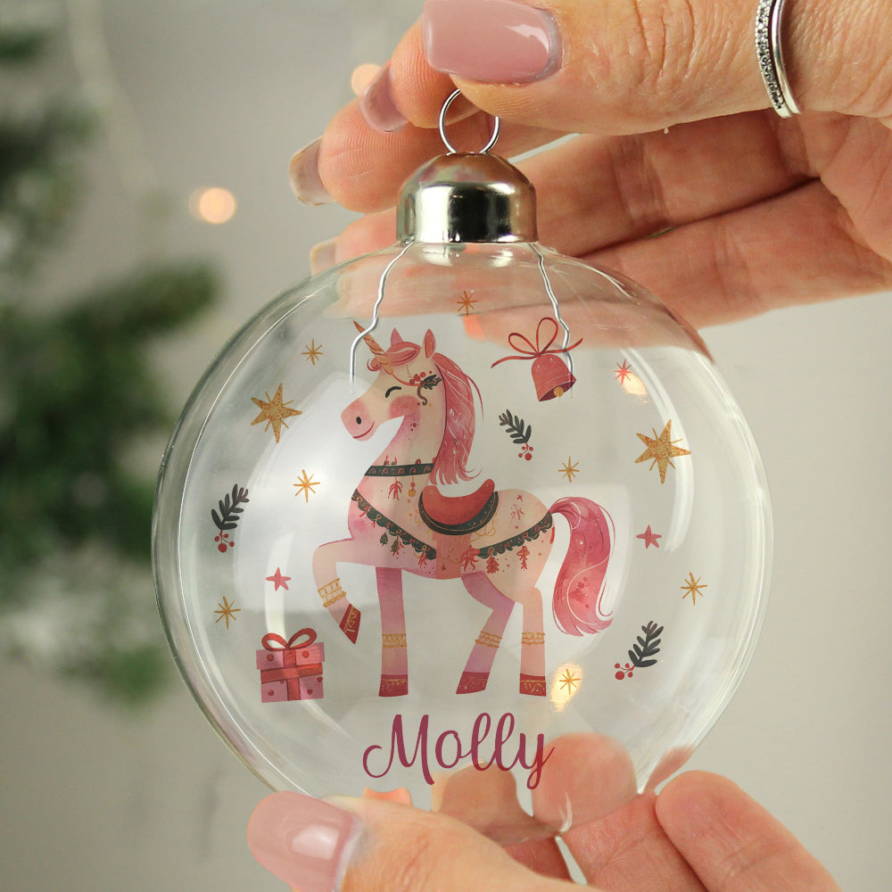 Decorative Christmas ornament with a pink unicorn design and the name 'Molly', held by a hand.