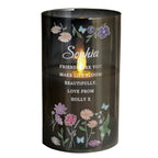 Candle in a black holder with floral designs and personalized text on a white background