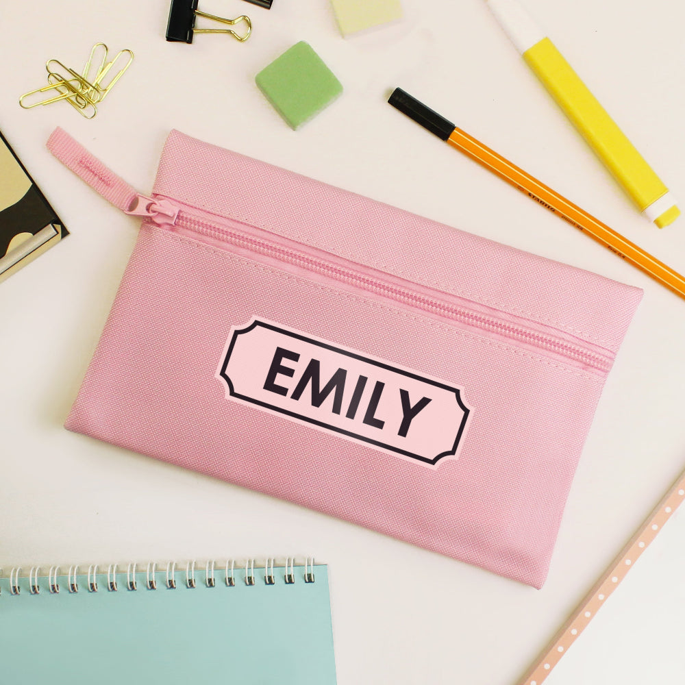 Pink pencil case with 'EMILY' label on a desk with stationery items