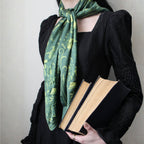 Person wearing a green patterned scarf holding two books against a neutral background