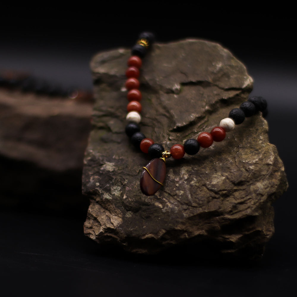 Beaded bracelet with red, black, and white beads on a dark rock background
