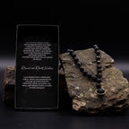 Lava stone necklace on a rock with descriptive card against a dark background