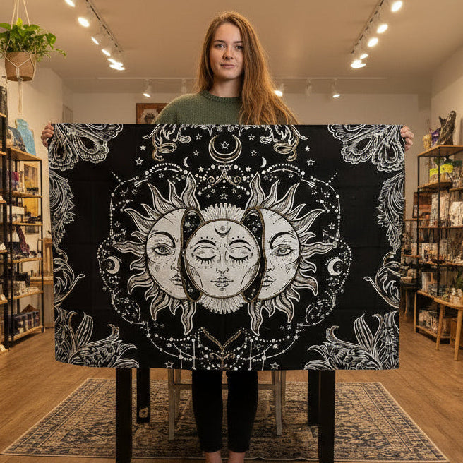 Person holding a large black and white tapestry with celestial designs.