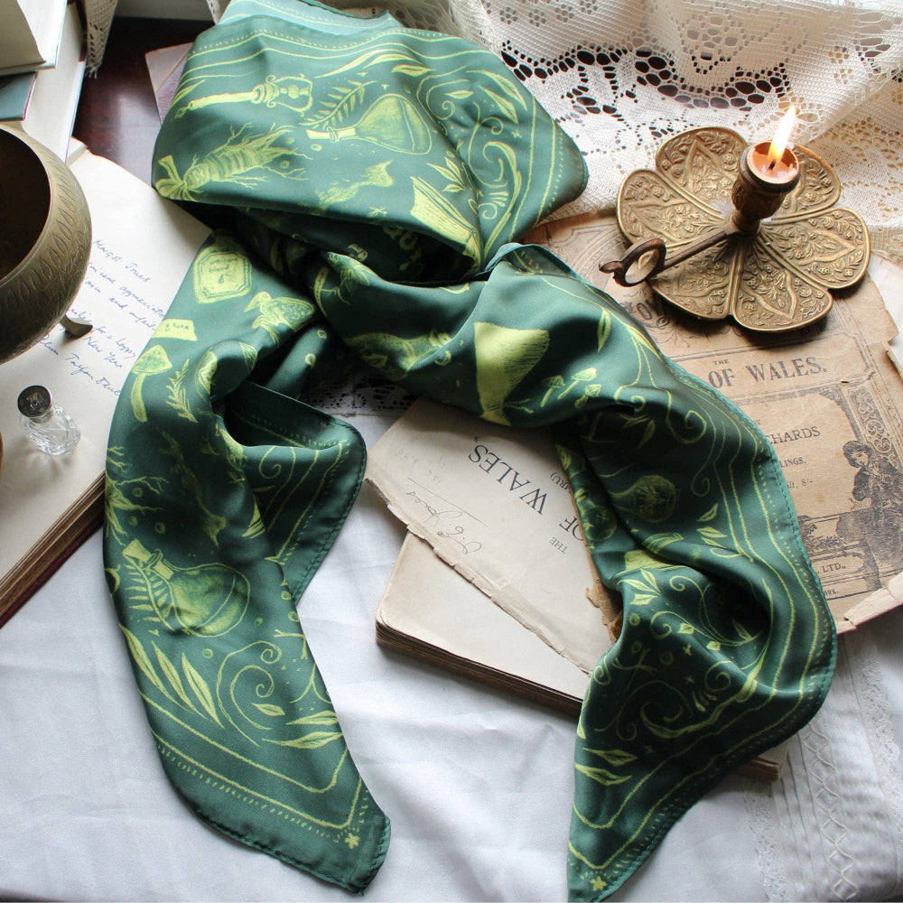 Green patterned scarf on top of books with a candle and decorative key in the background