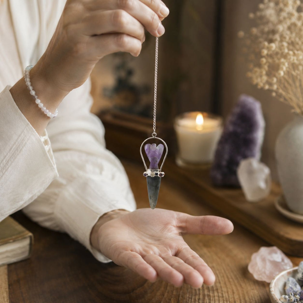 Person holding a crystal pendulum over their palm with a candle and crystals in the background