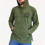A man wearing a washed olive green hooded sweatshirt with a black mandala-style chest graphic and drawstrings, paired with blue jeans, against a plain white background.