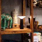 Black lamp on a wooden shelf with decorative items in the background