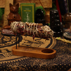 Smudging stick on a wooden stand with various items in the background