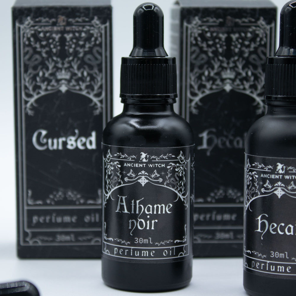 Black perfume oil bottles with decorative labels on a white background