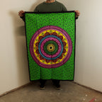 Person holding a colorful mandala tapestry with a green border.