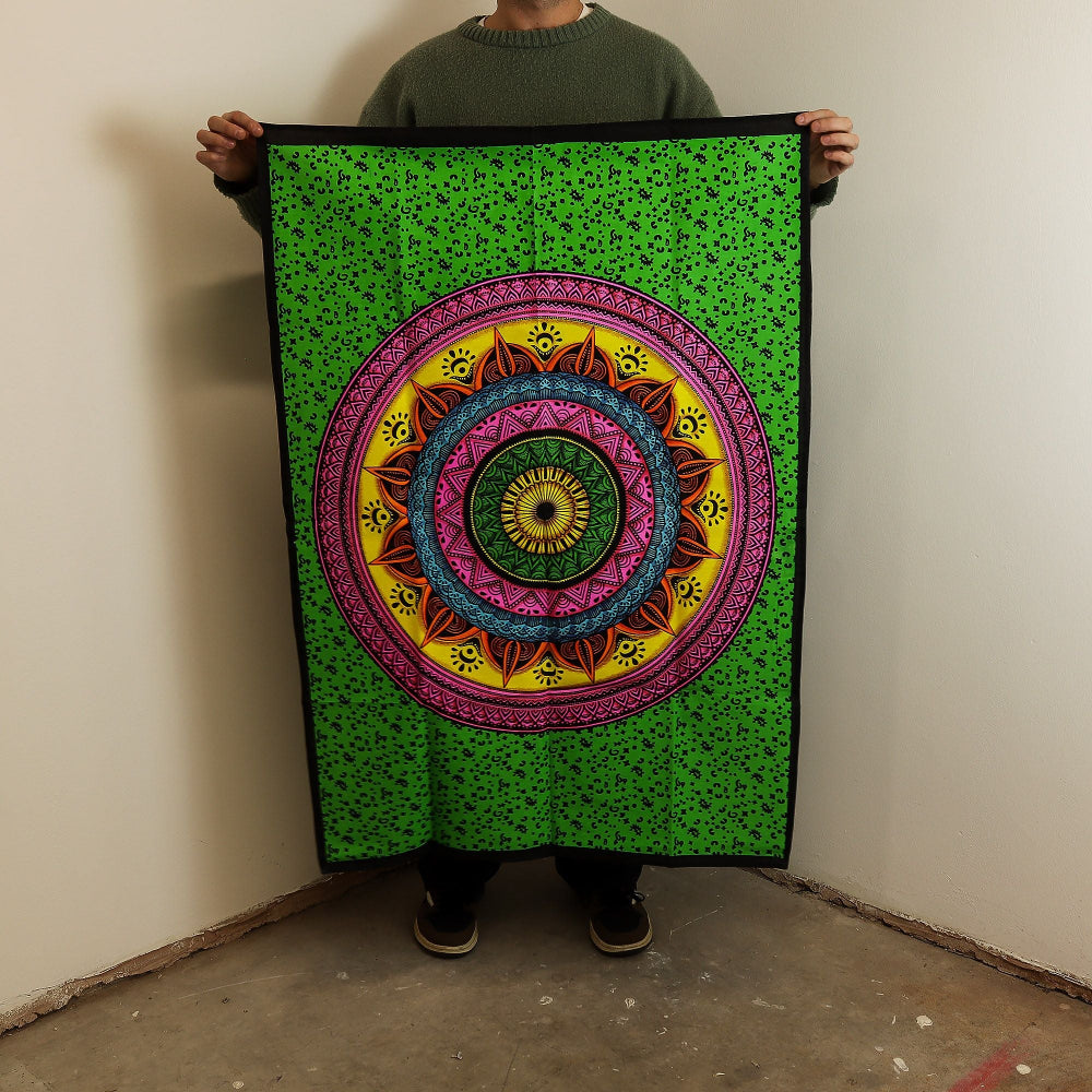 Person holding a colorful mandala tapestry with a green border.