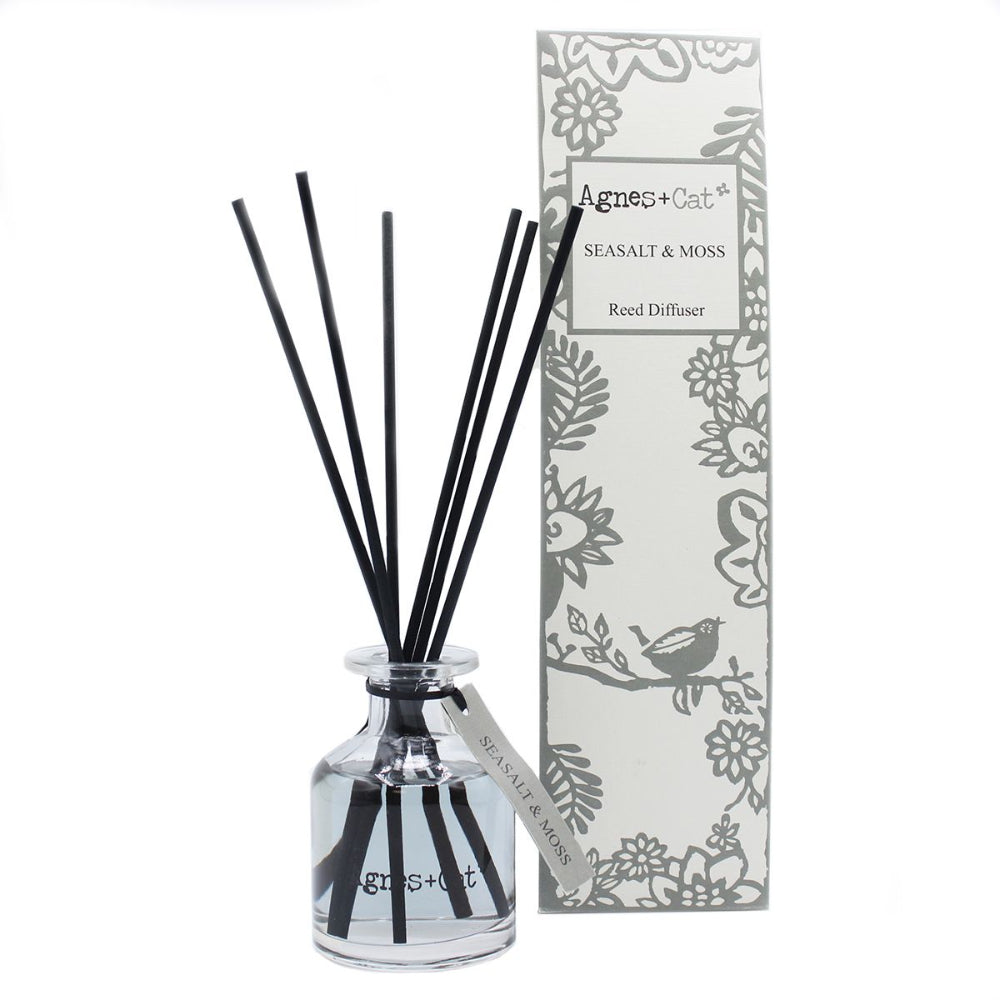 Reed diffuser with black sticks and a decorative box on a white background