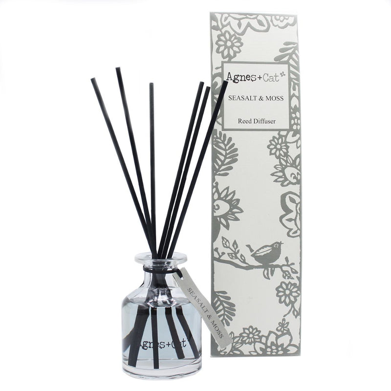Reed diffuser with black sticks and a decorative box on a white background