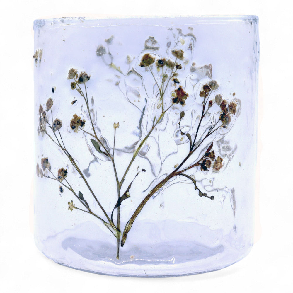 Clear glass candle holder with pressed flowers on a white background