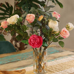 Bouquet of artificial flowers in a clear vase on a textured surface with a blurred background