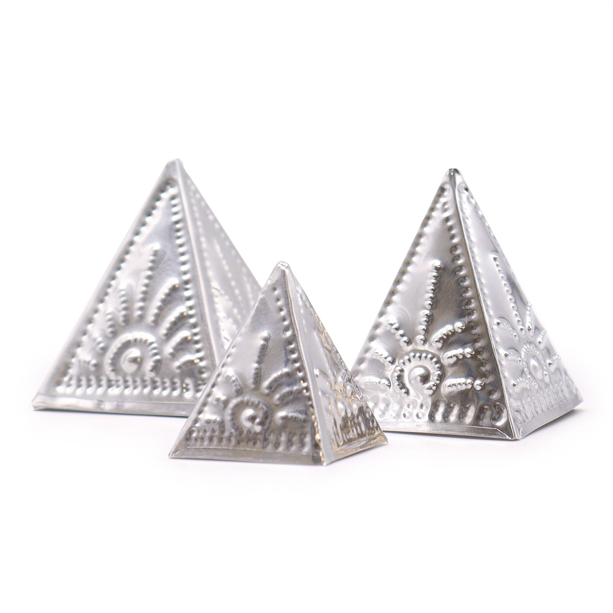 Three silver pyramidal objects with intricate designs on a white background