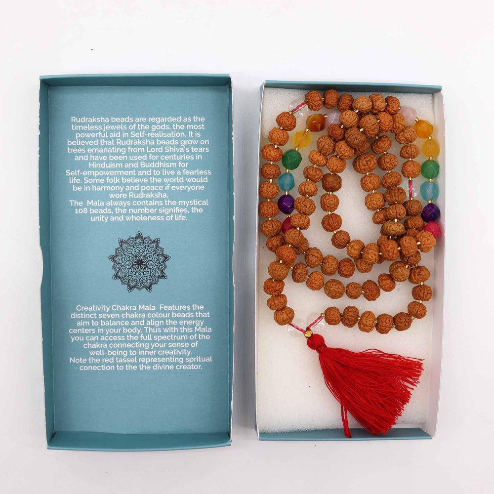 Mala beads with colorful stones and a red tassel in a box with descriptive text on a white background