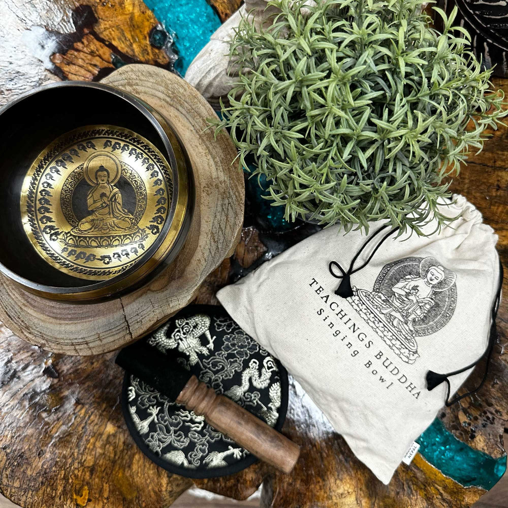 Buddhist singing bowl set with wooden mallet and pouch on a wooden surface