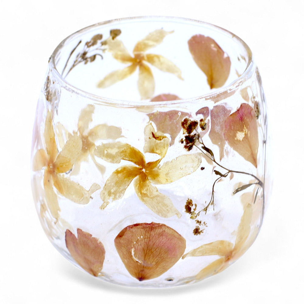 Clear glass with pressed flowers on a white background