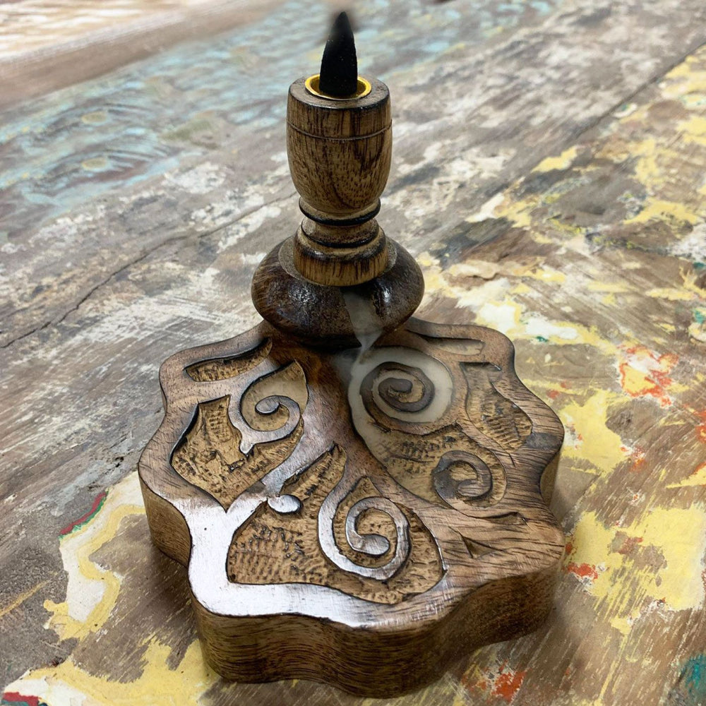 Wooden incense burner with intricate carvings on a textured surface