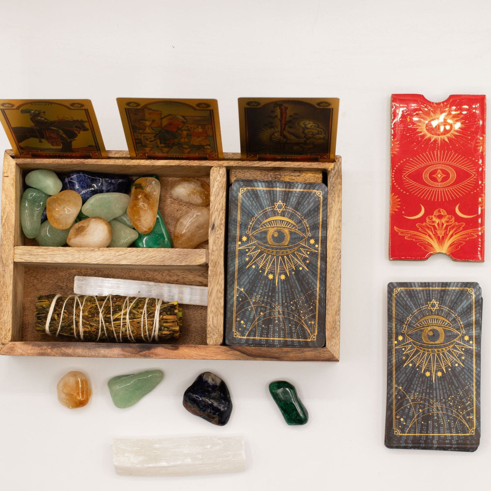 Wooden box with stones and wands, tarot cards, and a red book on a white background