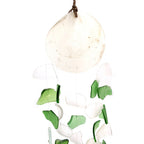 Decorative hanging with green and white glass pieces on a white background