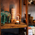 Decorative items including a teal elephant figurine and a candle lantern on a wooden shelf.