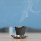 Incense cone with smoke on a blue background