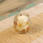Candle in a glass holder with floral design on a wooden surface