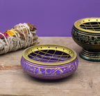 Decorative purple and gold incense burner on a wooden surface with a purple background