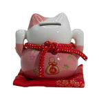 Pink and white cat-shaped money box with red string and pouch on a white background