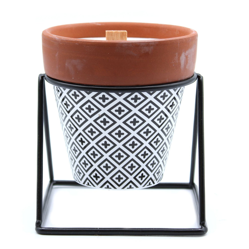 Terracotta pot on top of a patterned ceramic pot with a black metal stand on a white background