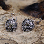 Pair of silver heart-shaped earrings with gold accents on a wooden surface